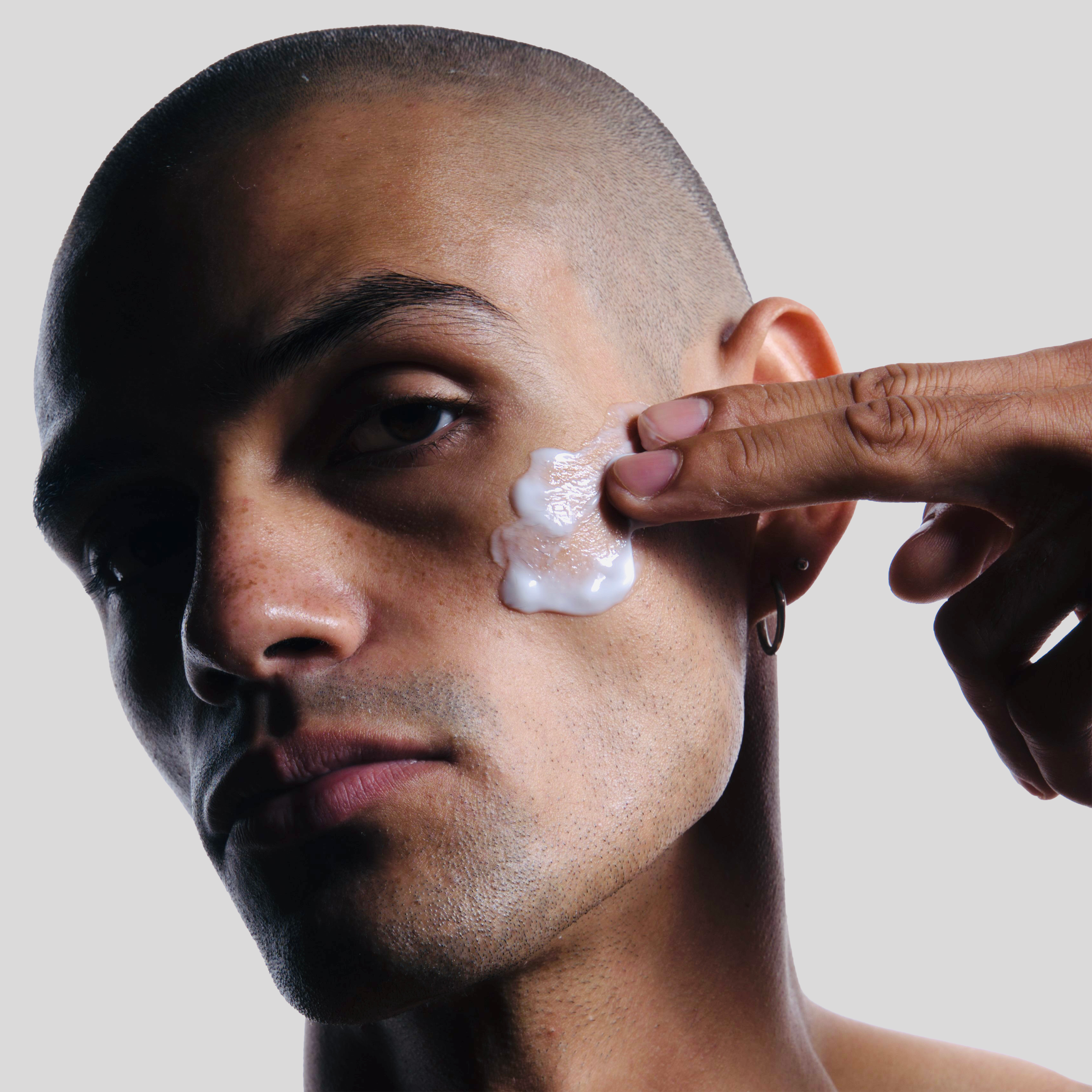 Male model with short hair applying Kaizen Seven Light Moisturizer to face